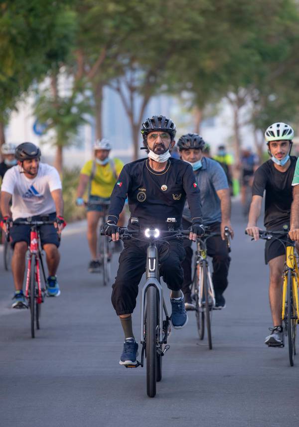 A group ride in the UAE, riders setting off together on a tree-lined road
