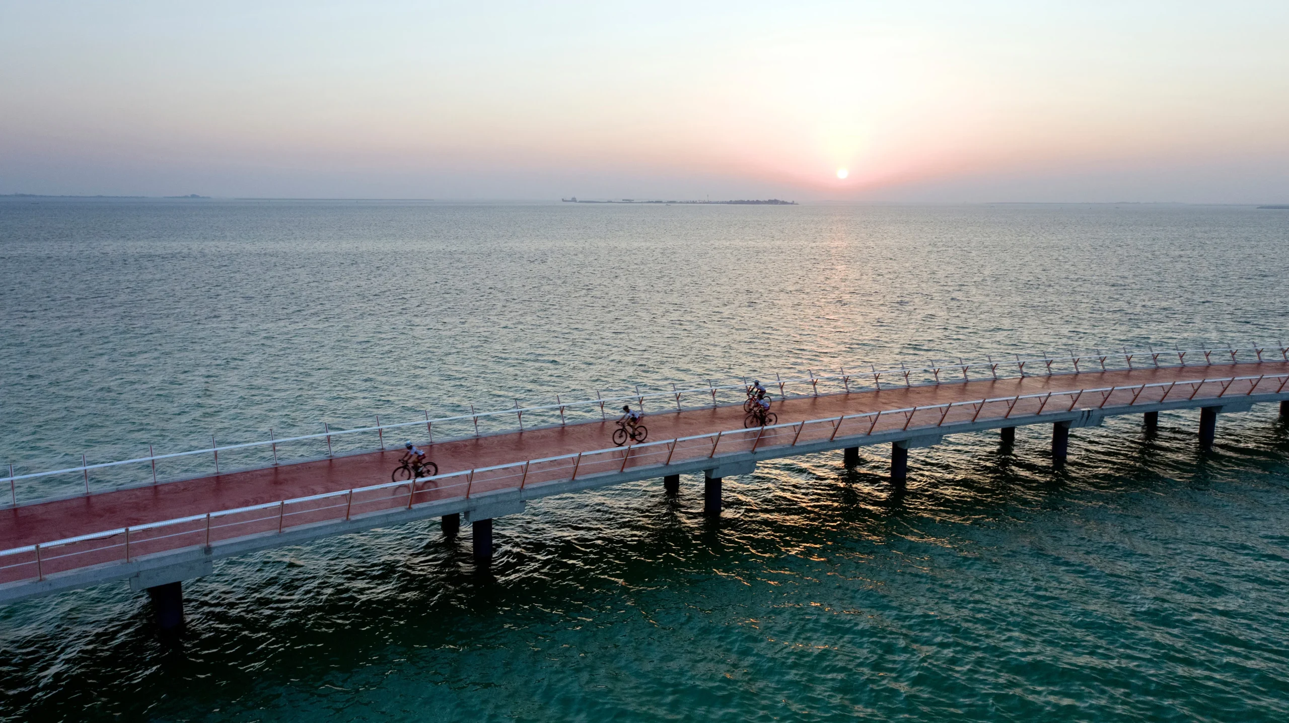 Cyclists on the Al Hudayriyat bridge at sunset